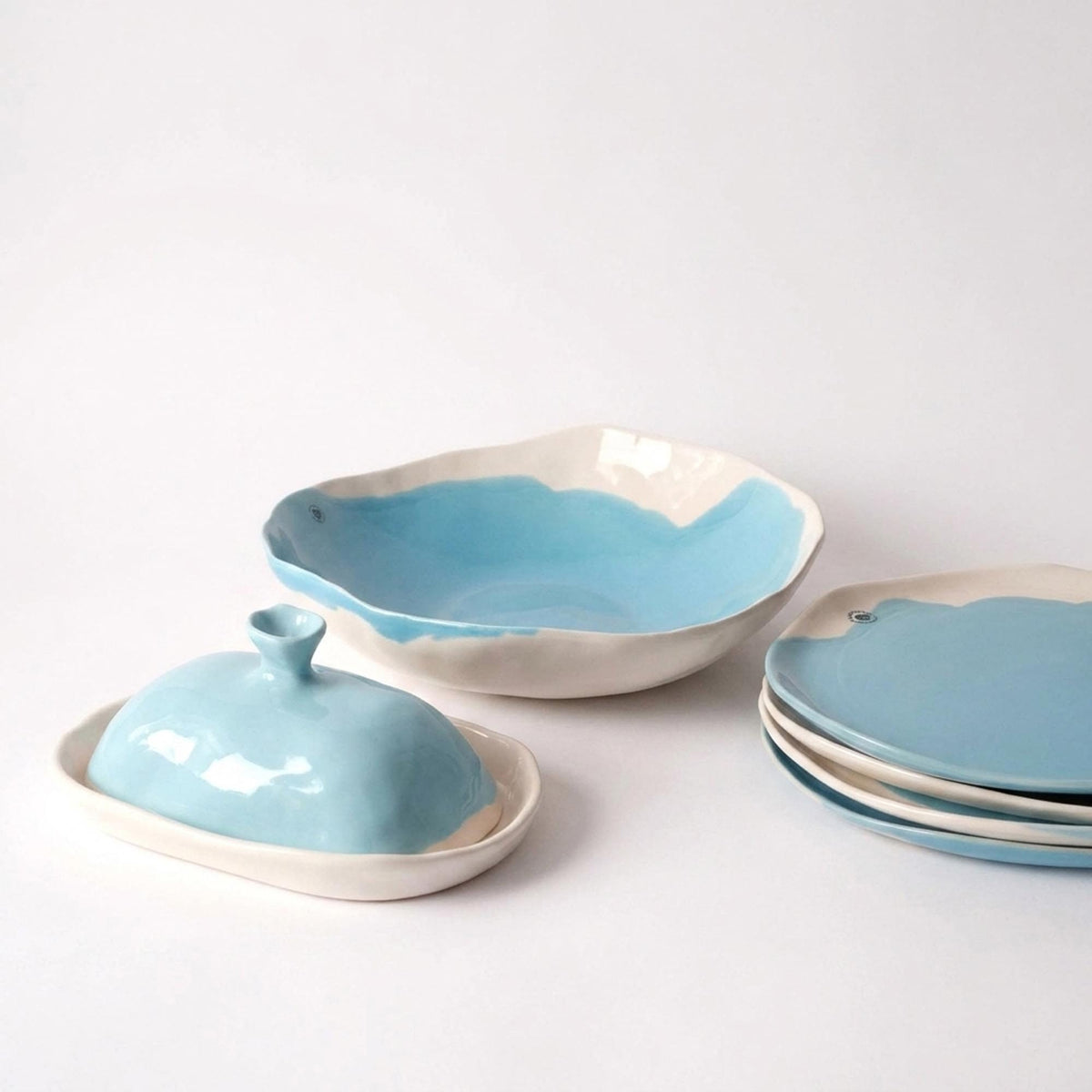 Sky blue handmade butter dish with a matching serving bowl and stacked plates