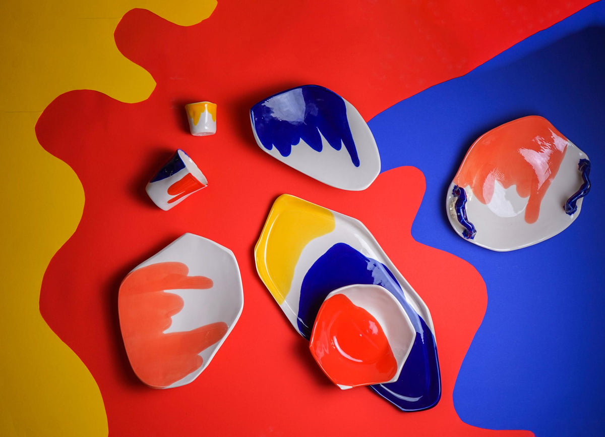 Bauhaus colour palette porcelain plates, bowls and cups in red, yellow and blue on a primary colour background