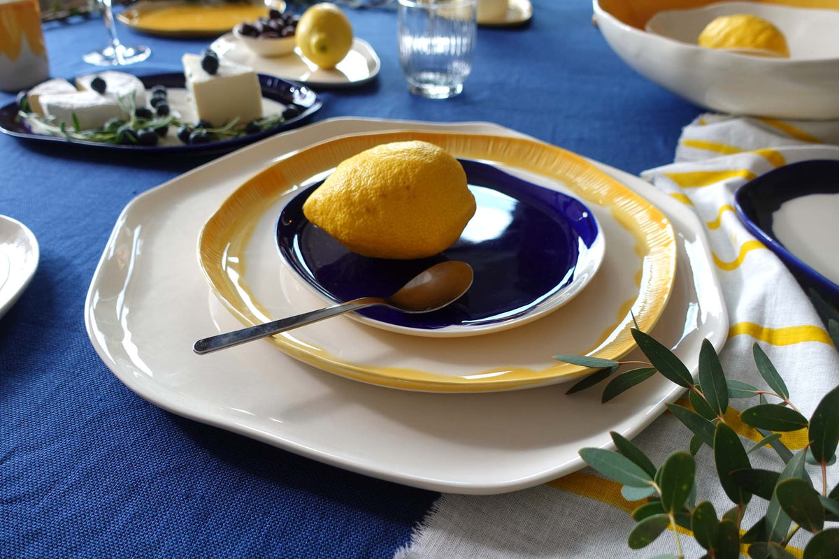 Royal Blue and yellow handmade porcelain plates with a lemon on a blue tablecloth