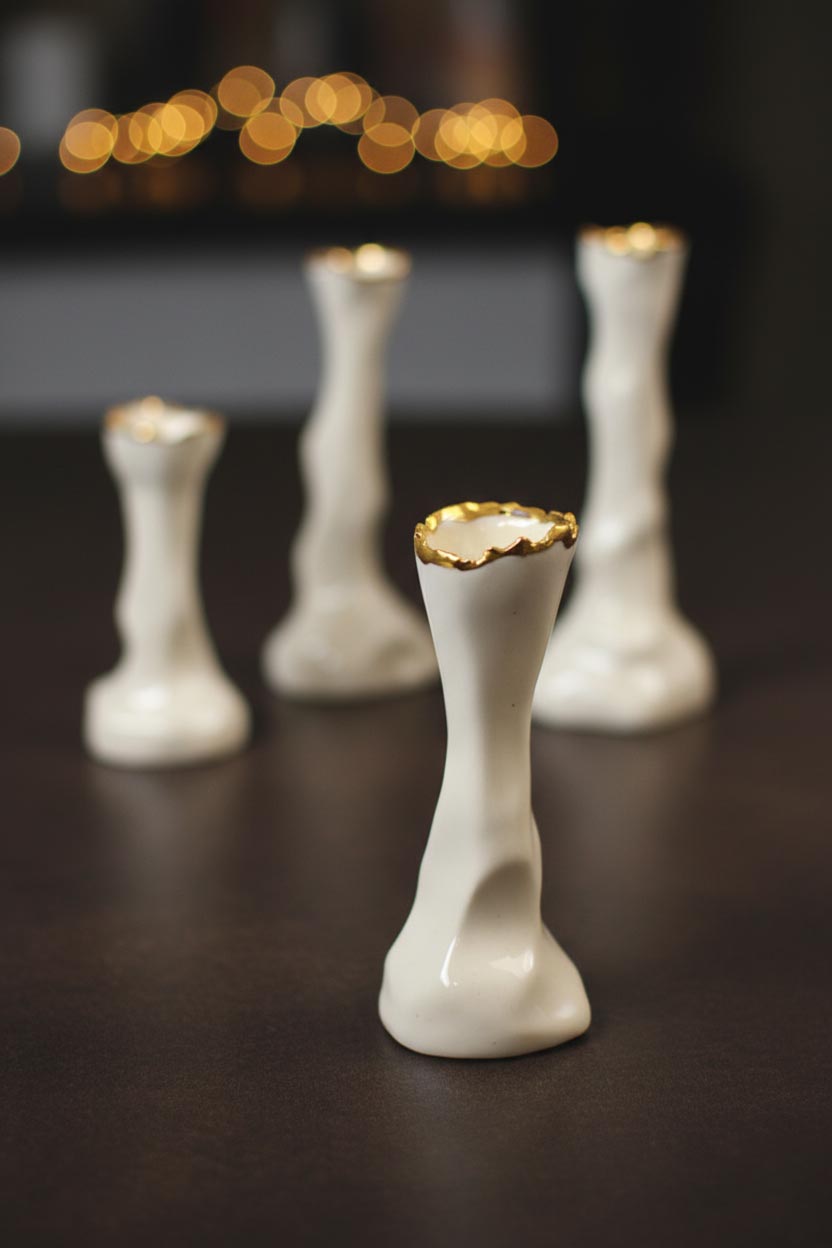 Ivory and gold porcelain candle holders against a dark background