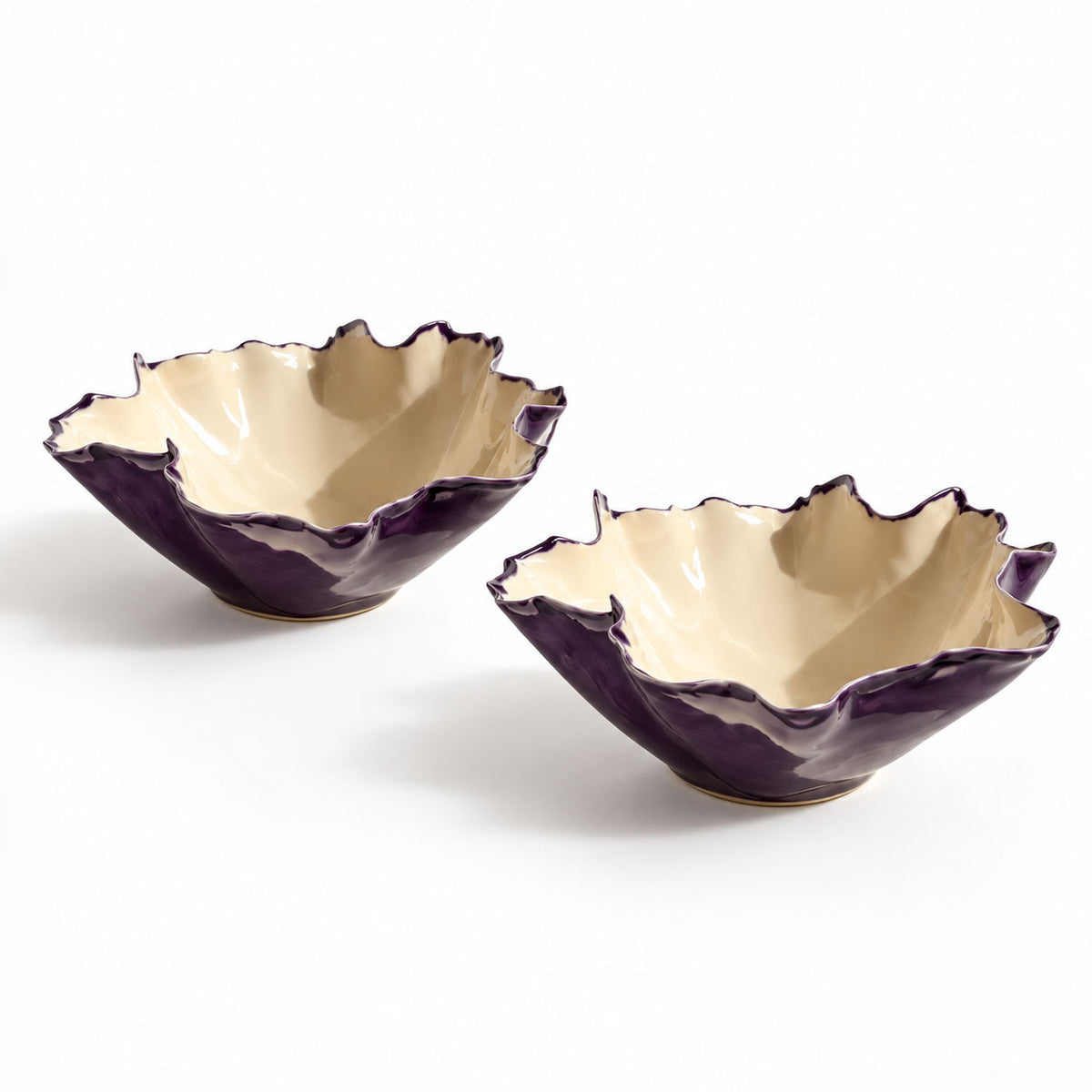 Two handmade Blossom ceramic bowls with aubergine exteriors, warm ivory interiors and folded rims on a white background
