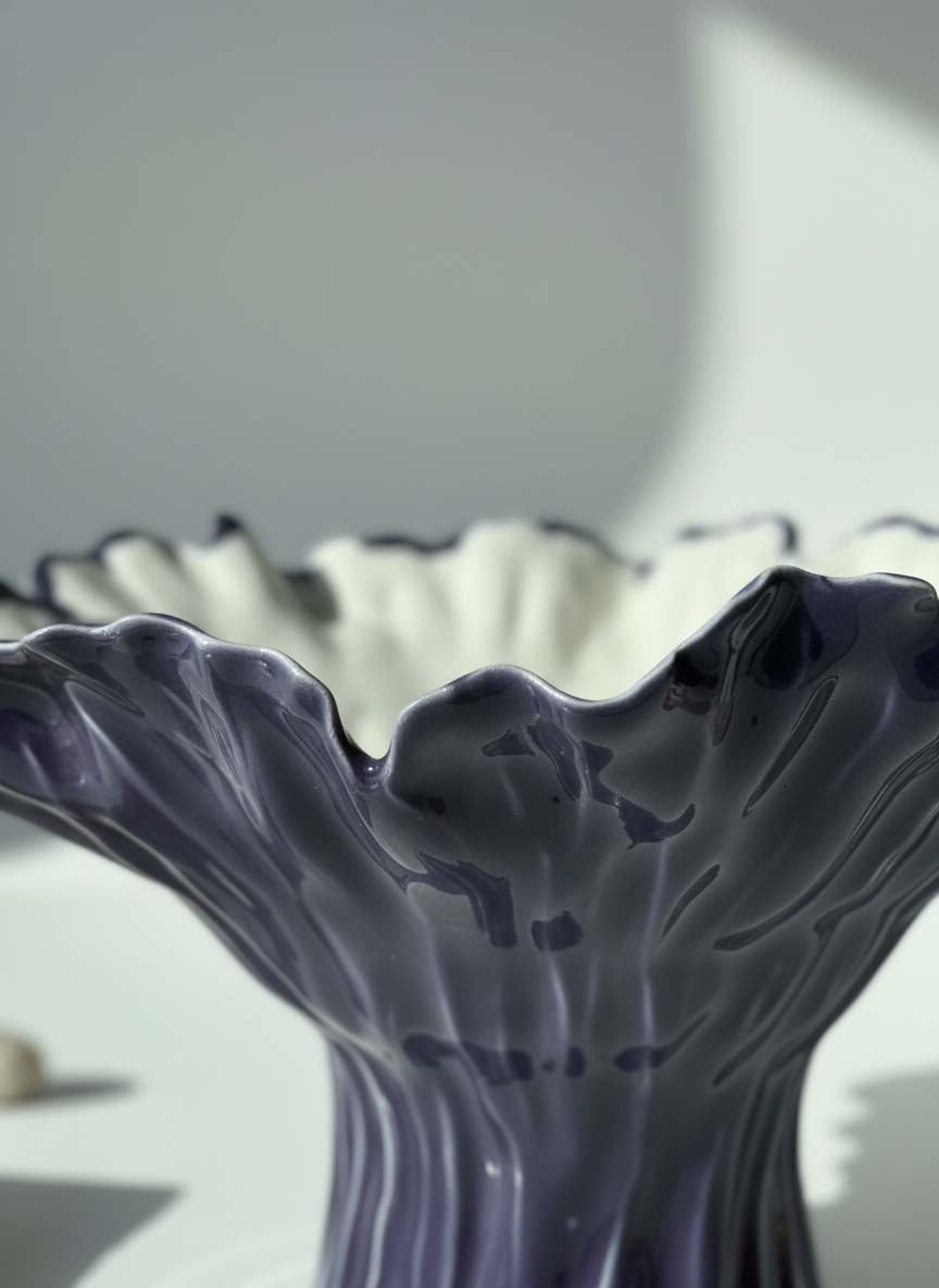 Close-up of sculptural folds on an aubergine ceramic pedestal bowl