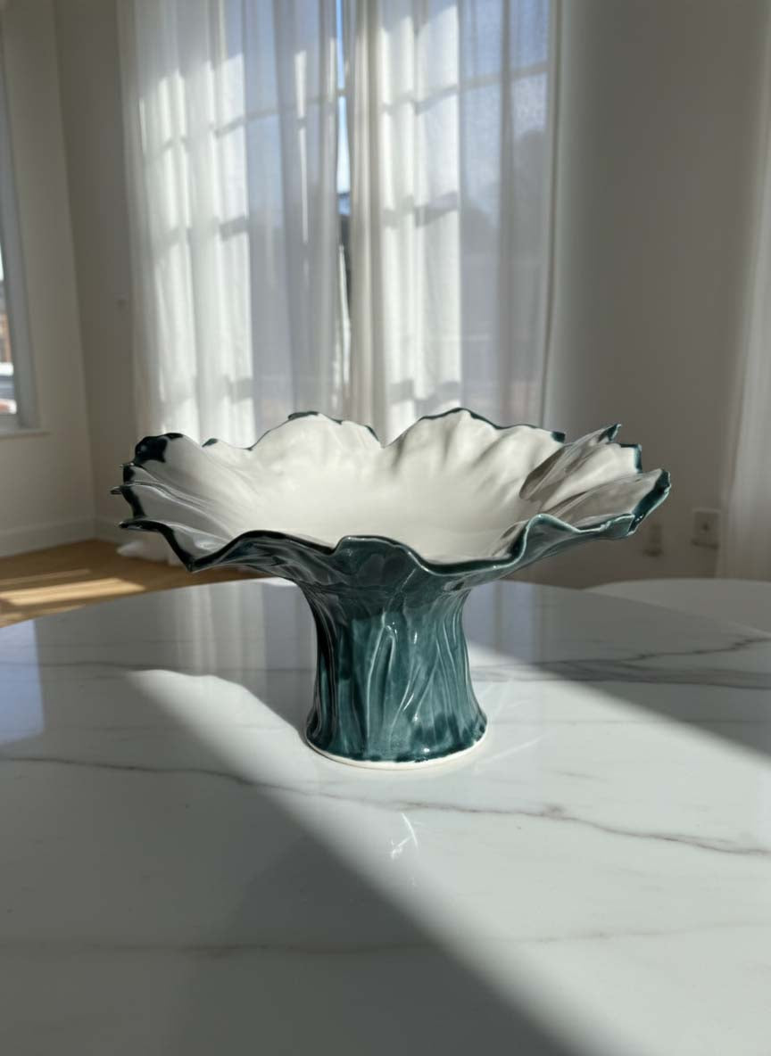 Petrol-green sculptural pedestal bowl on a sunlit table by a window