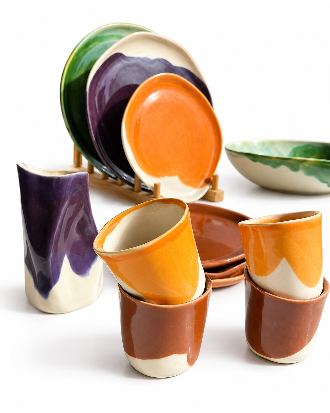 Close-up of autumn-glazed ceramic plates and cups in green, purple, orange and brown
