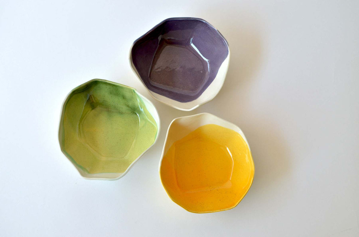Purple, green and yellow handmade ramen bowls viewed from above