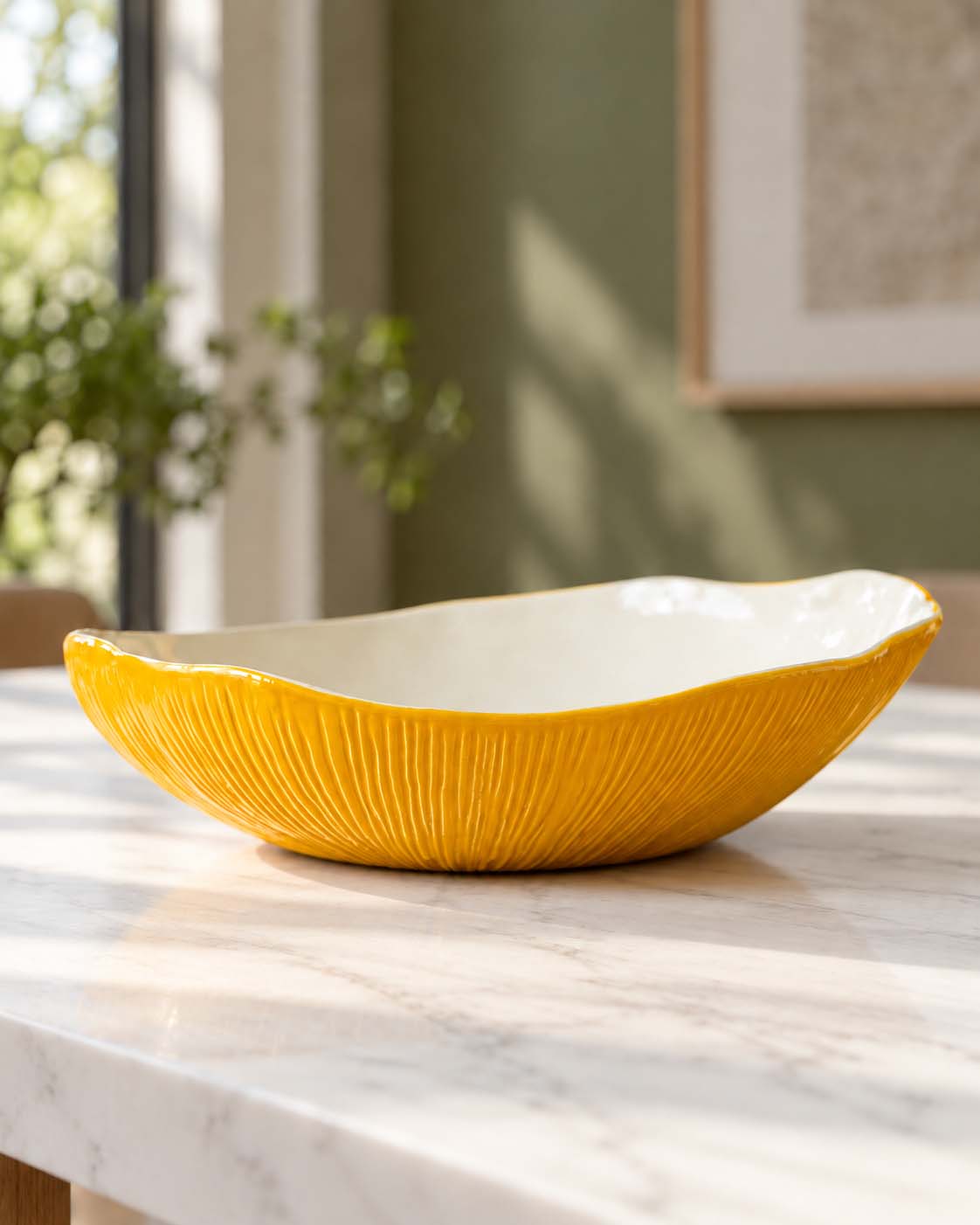 Yellow textured ceramic serving bowl with an ivory interior on a marble table