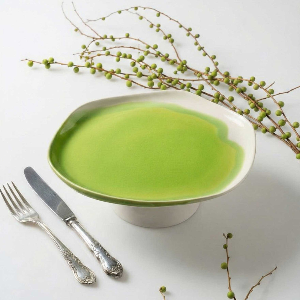 Artistic Cake Stand in lime green glaze with vintage cutlery and a branch of green berries