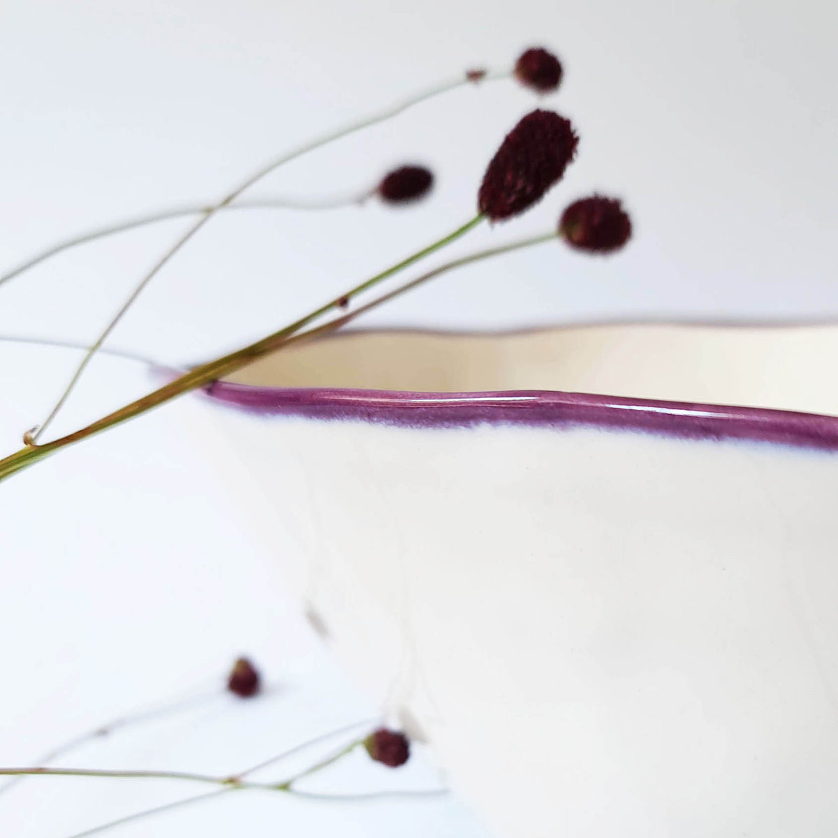 Close-up of a fine aubergine glaze rim on an ivory ceramic serving bowl