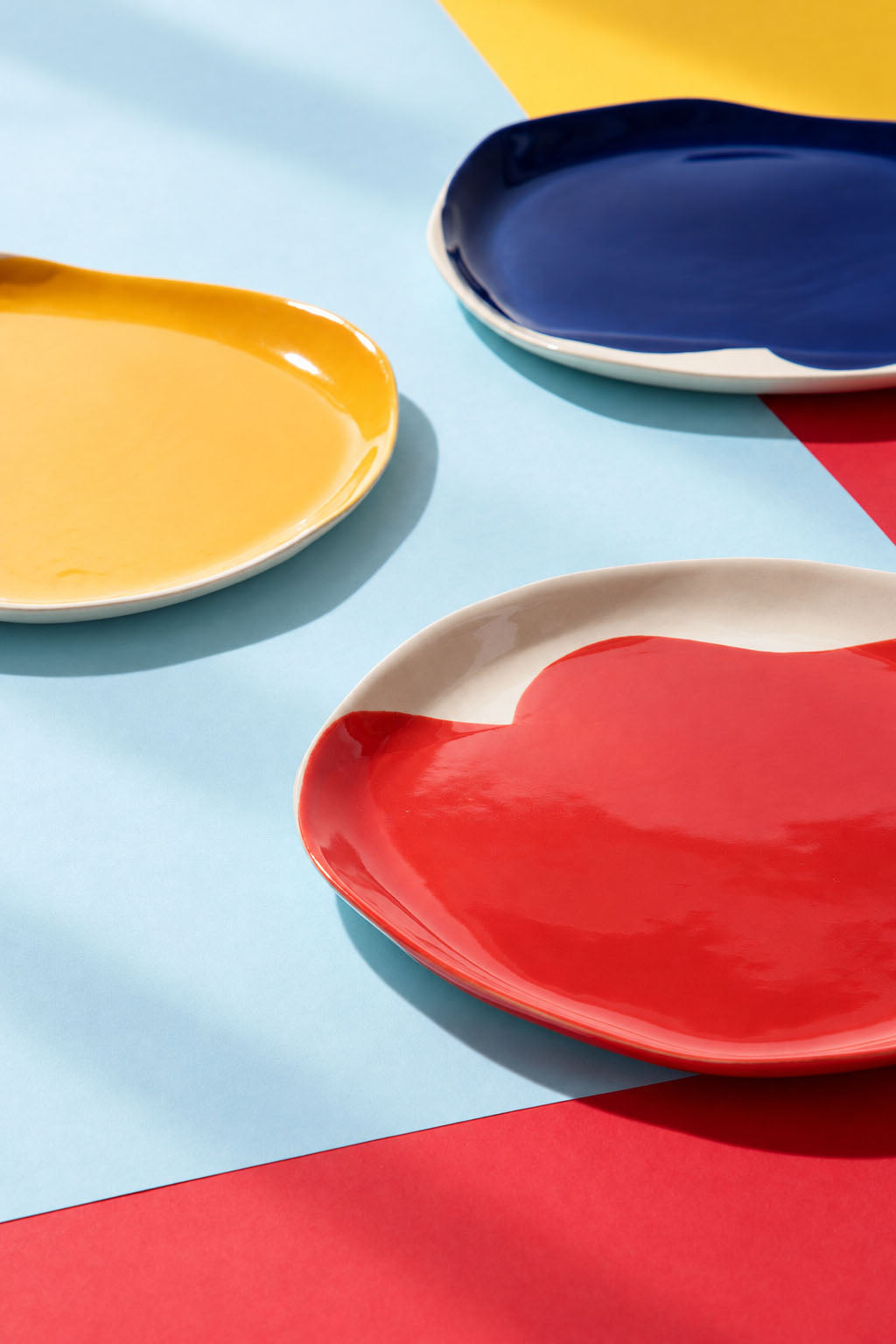 Red, yellow and cobalt blue BAUHAUS ceramic plates on overlapping coloured paper