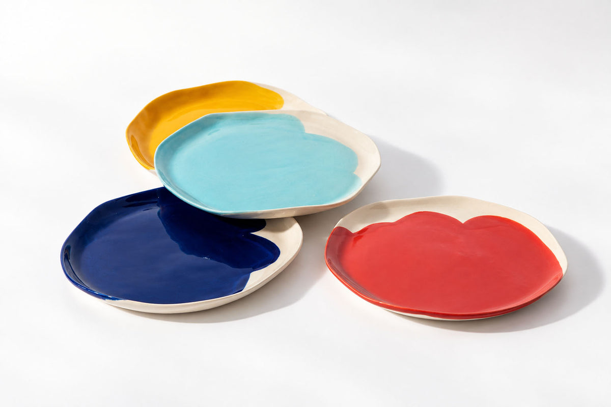 Four BAUHAUS ceramic plates with organic rims in cobalt blue, red, sky blue and yellow on white