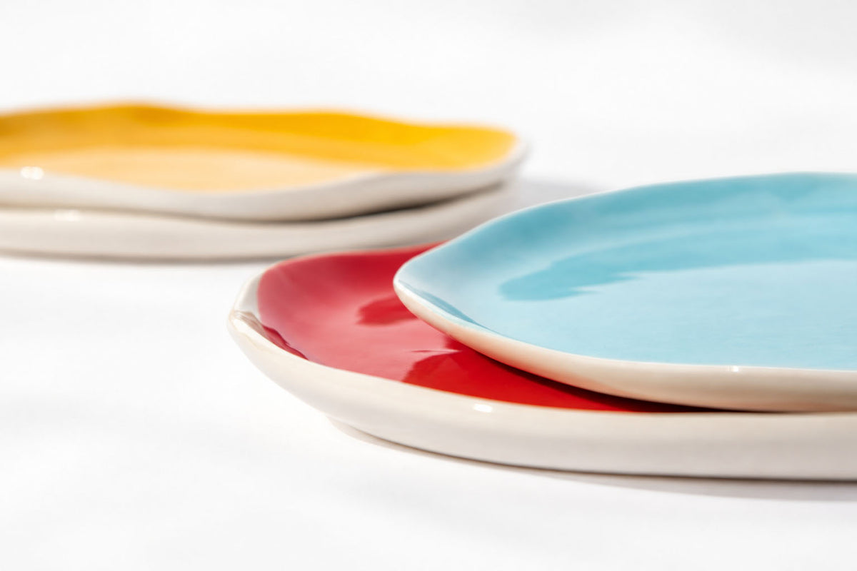 Close side view of overlapping sky blue, red and yellow BAUHAUS plates with ivory rims