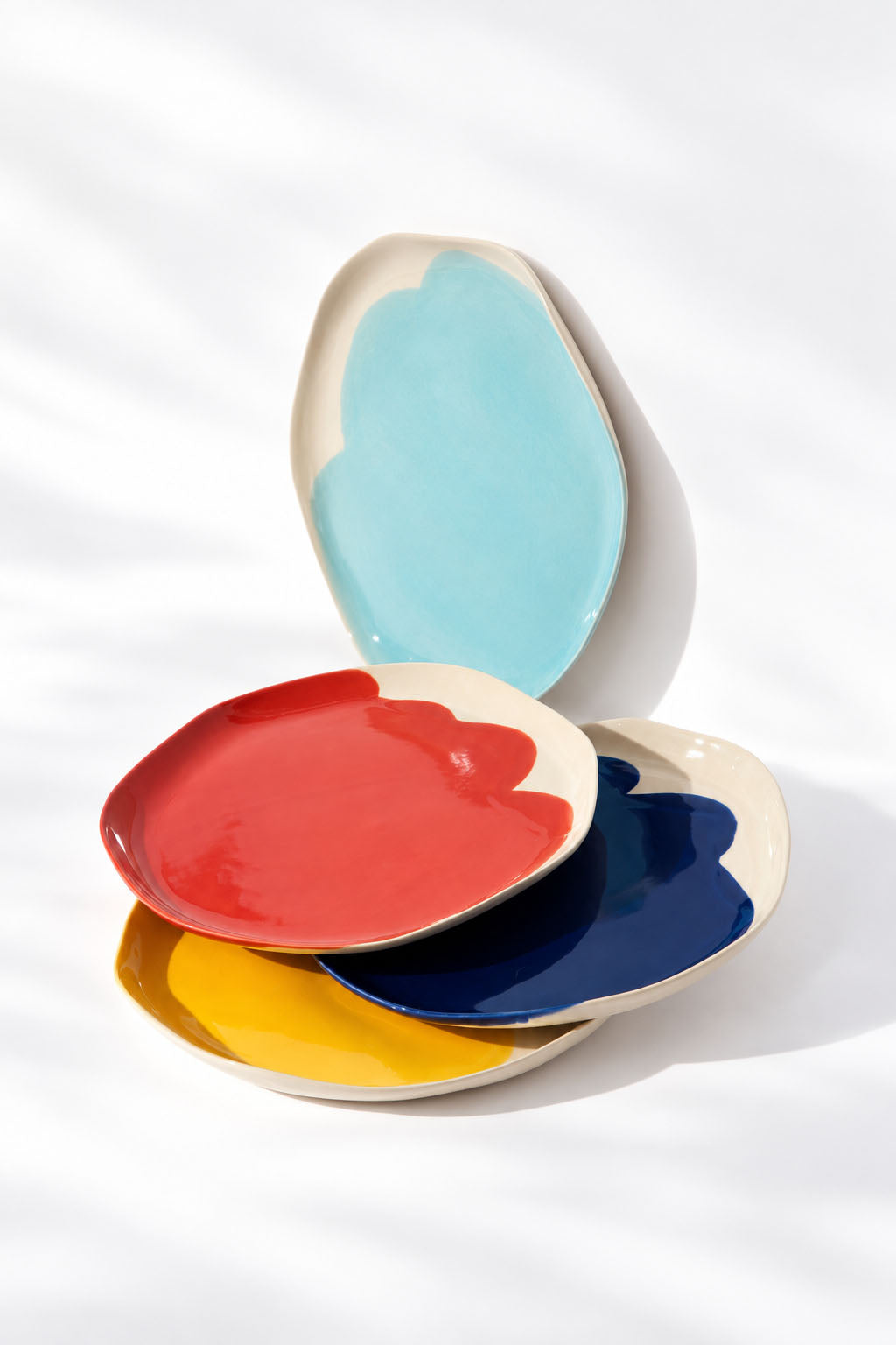 Sky blue BAUHAUS plate standing behind overlapping red, cobalt blue and yellow ceramic plates