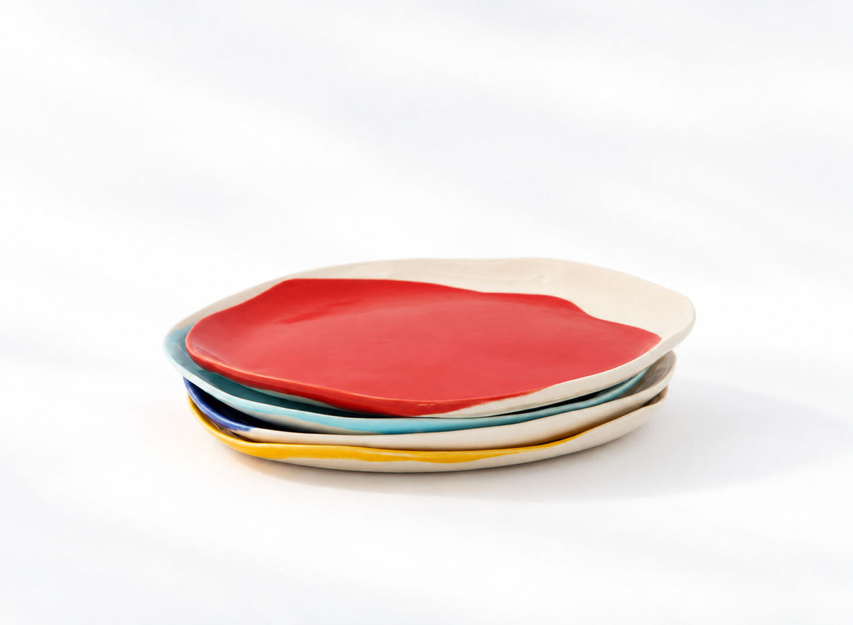 Stack of four BAUHAUS ceramic plates with a red plate on top on a white background