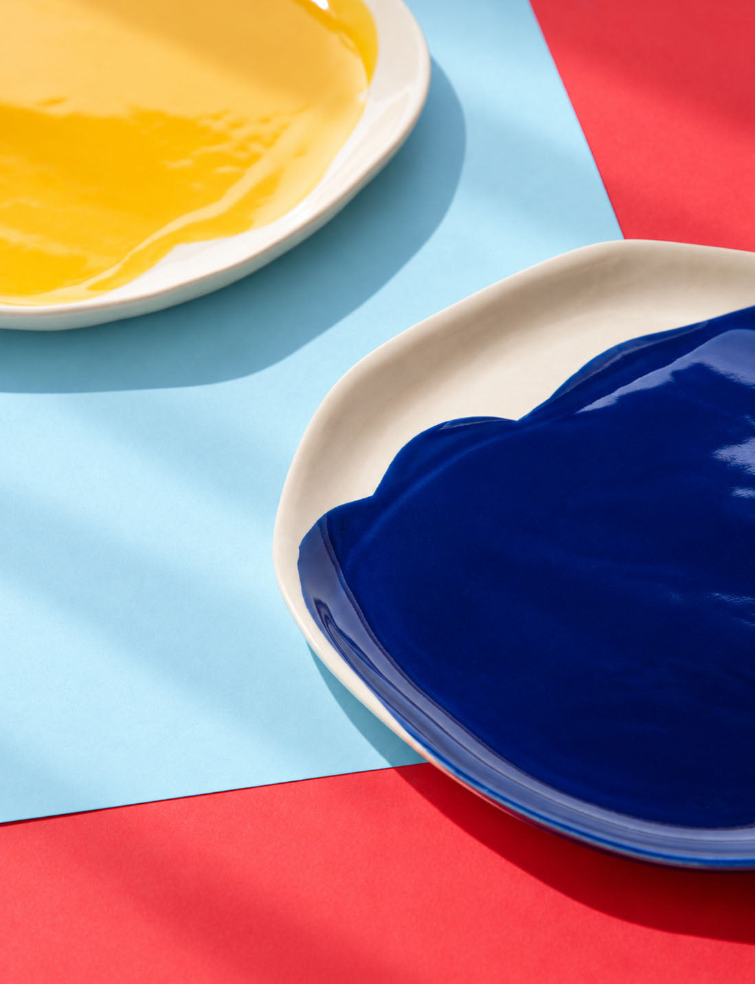 Detail of yellow and cobalt blue BAUHAUS ceramic plates on red and sky blue paper