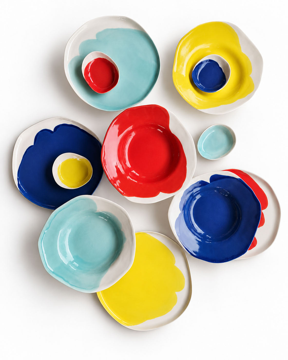Overhead composition of BAUHAUS ceramic plates, bowls and small dishes in red, yellow, sky blue and cobalt blue