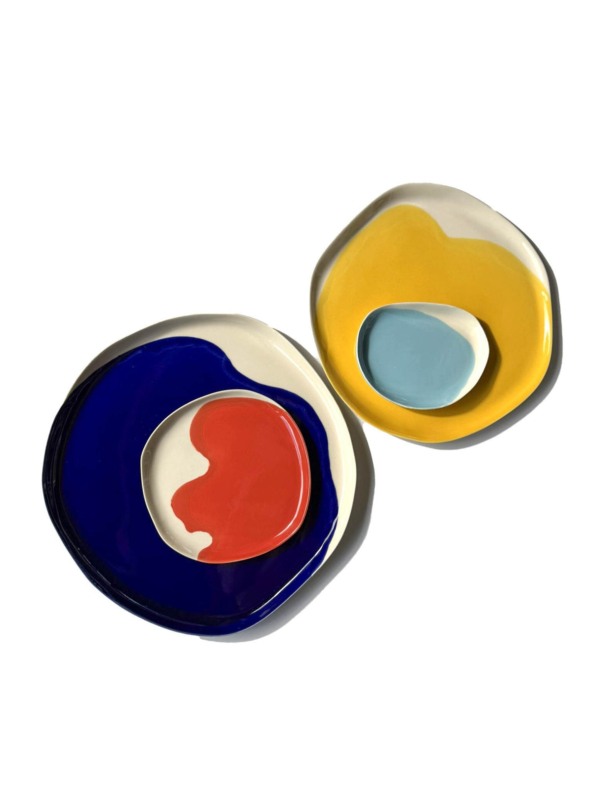 Two nested stacks from the Bauhaus Plates Set in blue, red, yellow and sky blue glaze
