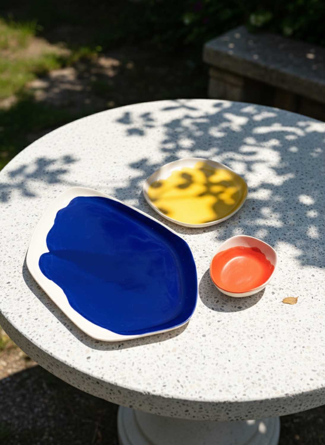 Bauhaus Porcelain Set in cobalt blue, yellow and coral glaze on a sunlit terrazzo garden table