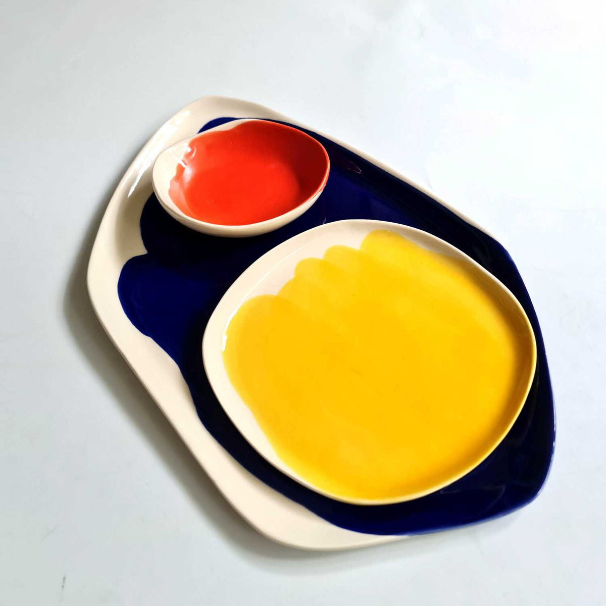 Bauhaus Porcelain Set with red dip bowl and yellow plate on a royal blue brushed platter
