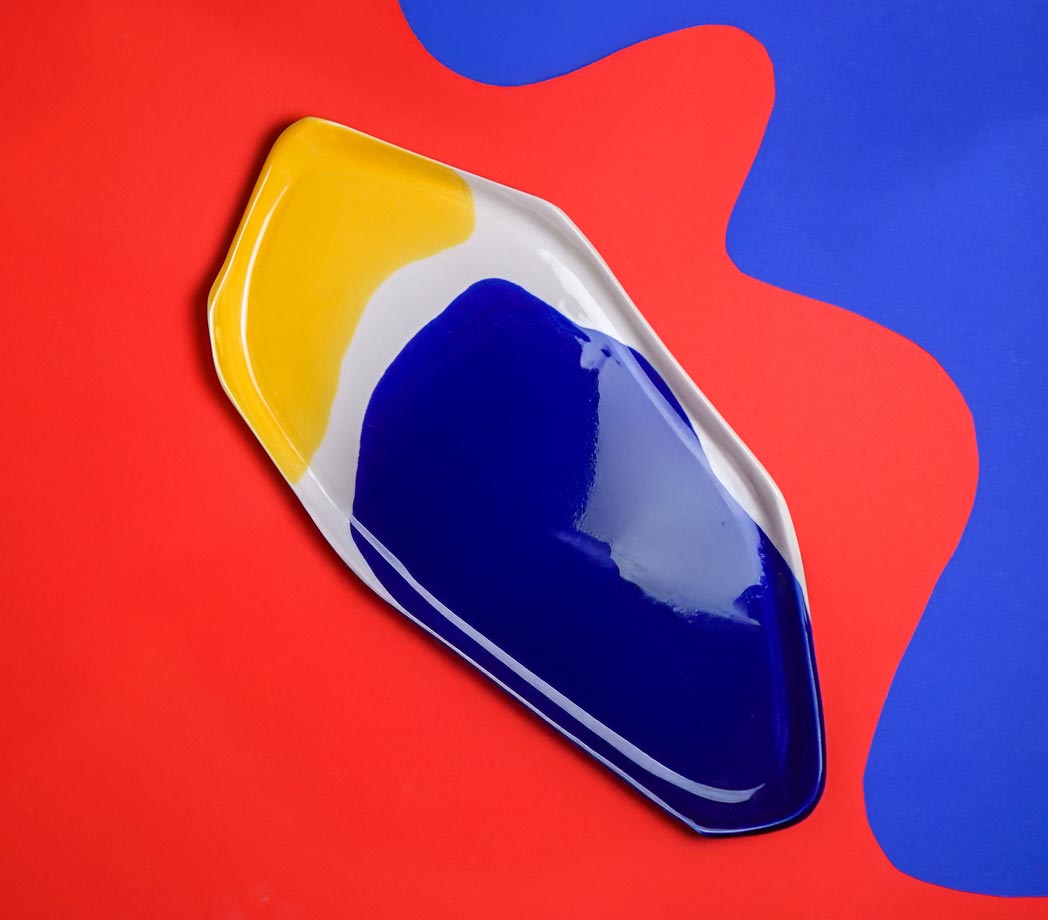 Bauhaus Serving Tray in cobalt blue and yellow glaze on a red and blue background