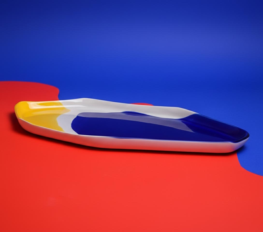 Side view of the long Bauhaus Serving Tray in blue, white and yellow glaze on red