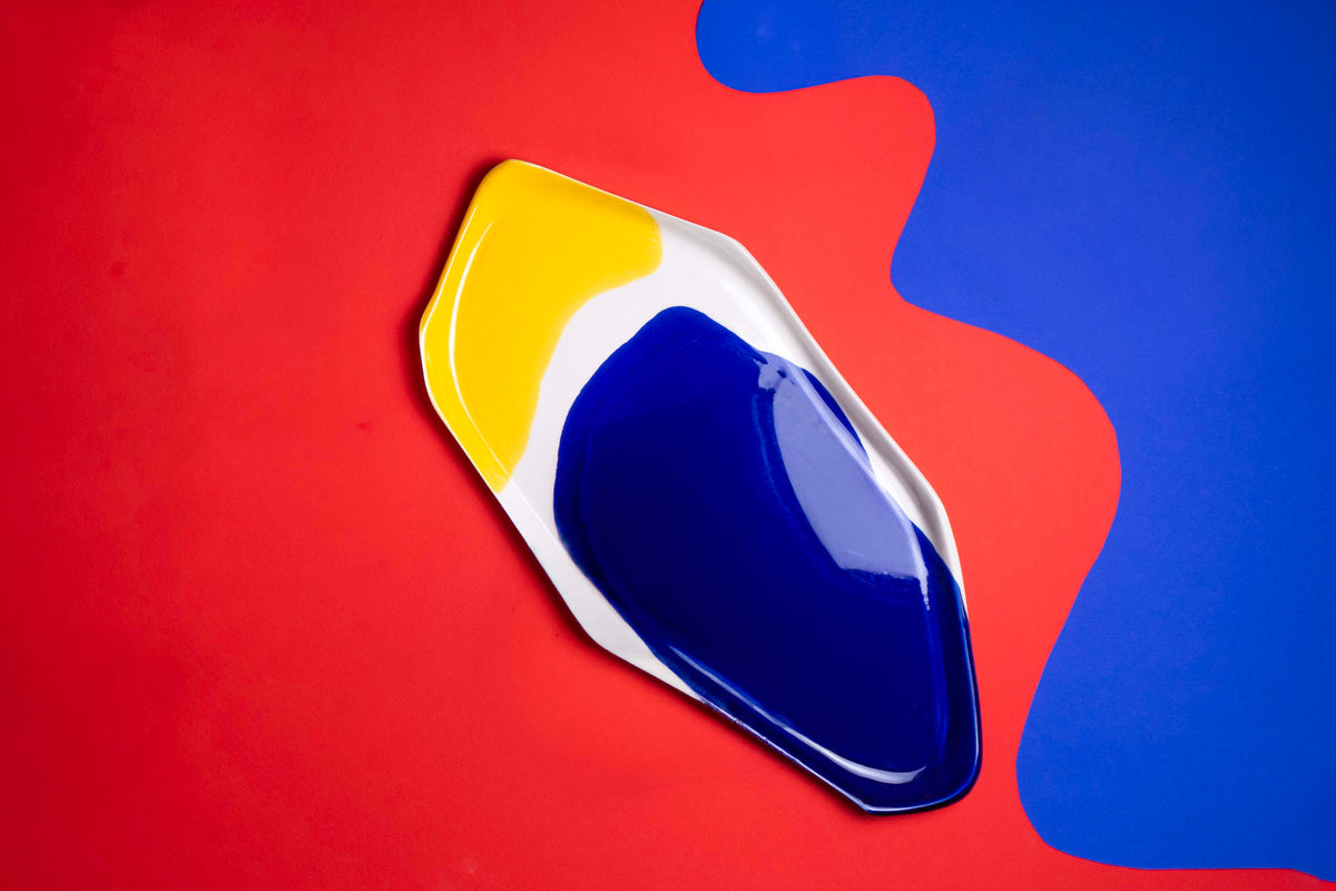 BAUHAUS ceramic serving tray with cobalt blue and yellow glaze on red and blue paper