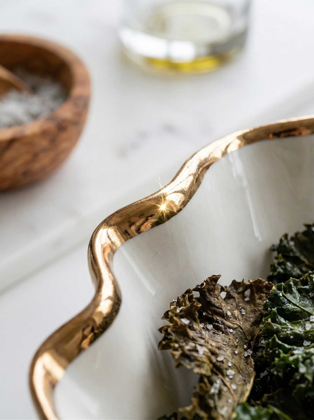 Close-up of the wavy copper lustre rim on a handmade porcelain Blossom bowl holding kale chips