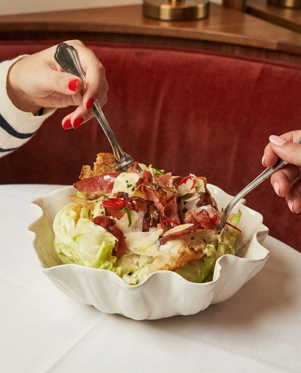 Salad served from a large white Blossom porcelain serving bowl at a restaurant table