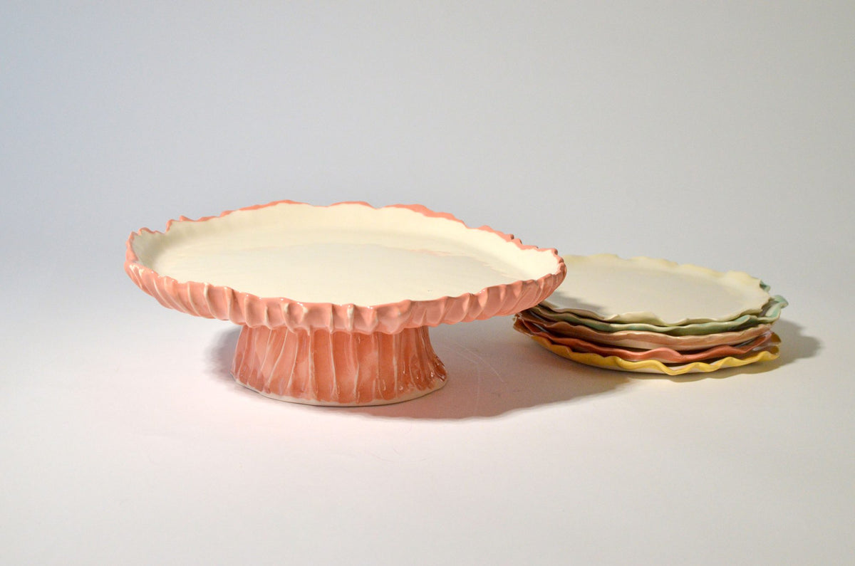 Pink Blossom ceramic cake stand beside a stack of colourful plates