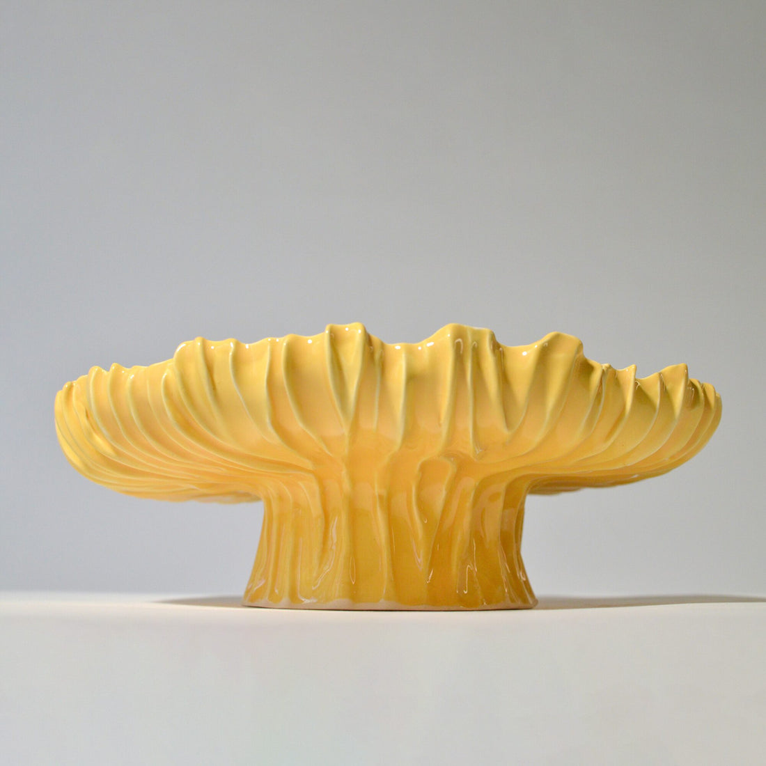 Yellow Blossom cake stand with a fluted rim and ribbed pedestal on white