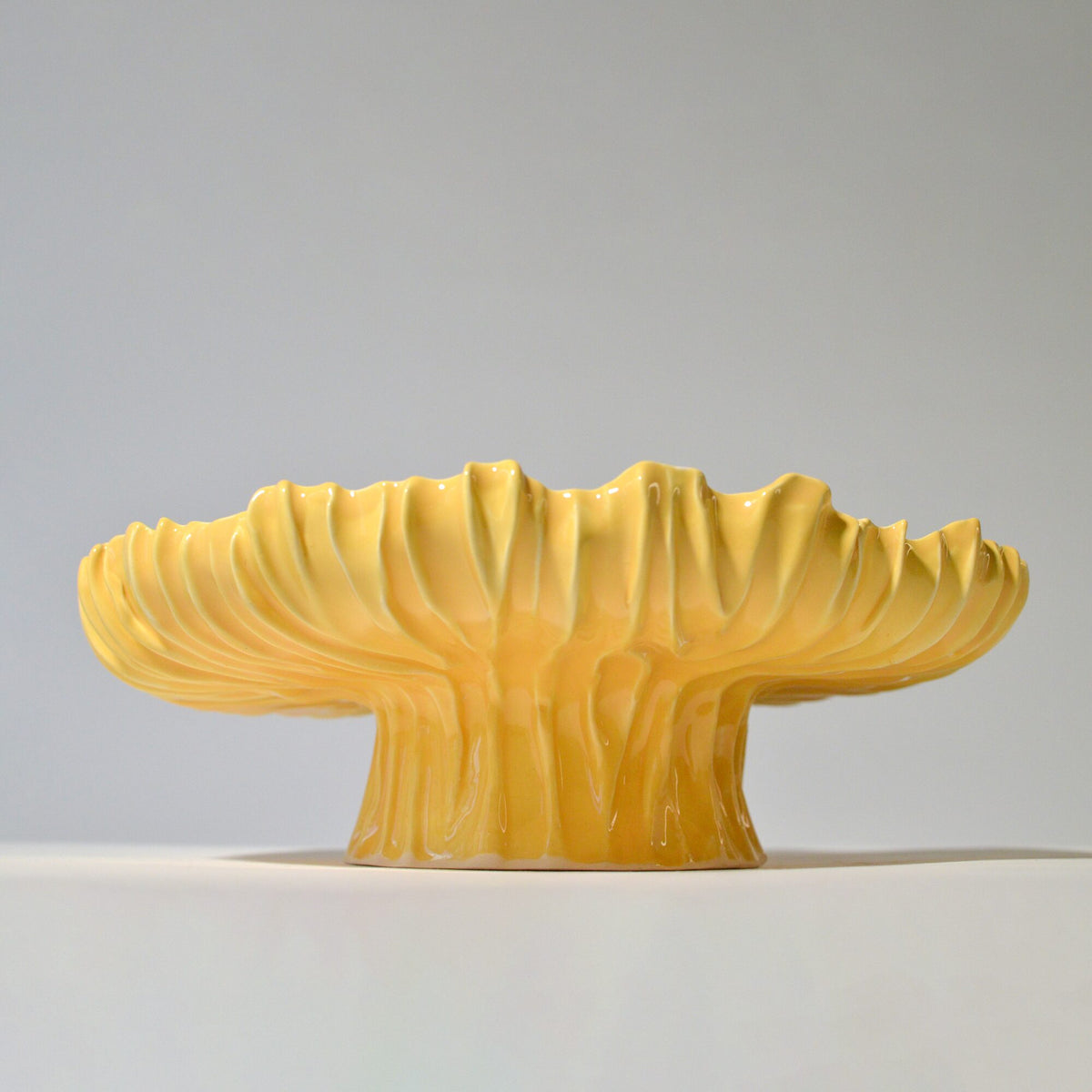 Yellow Blossom cake stand with a fluted rim and ribbed pedestal on white
