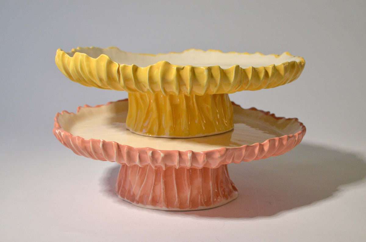 Yellow and pink Blossom ceramic cake stands stacked on a white background