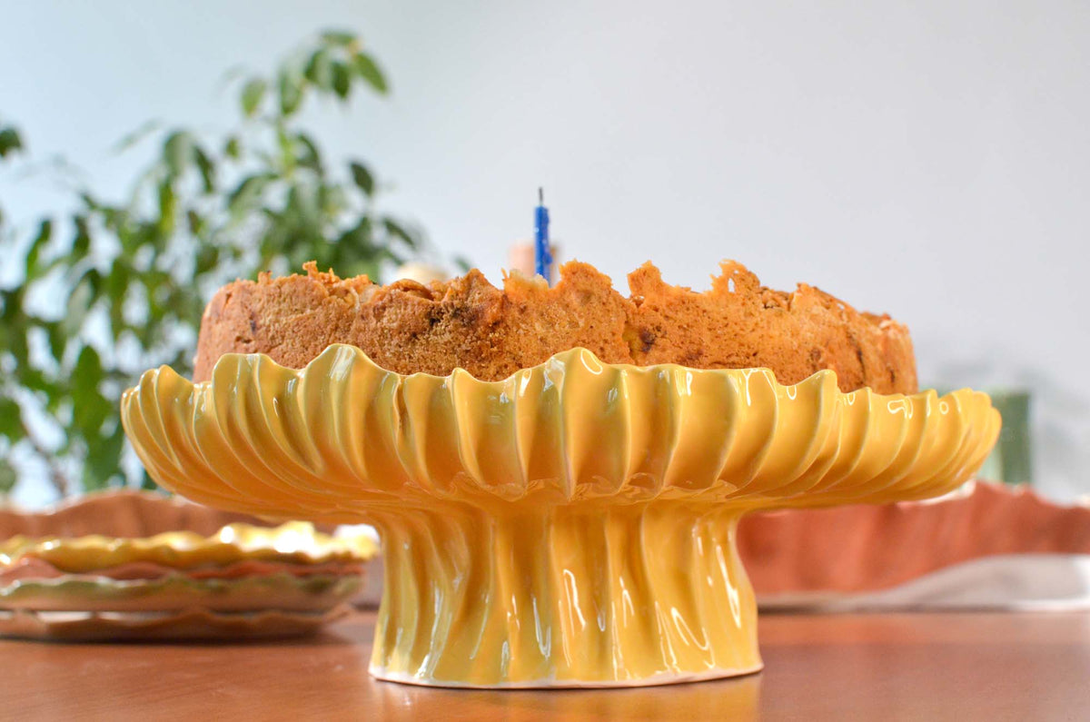 Yellow Blossom ceramic cake stand holding a cake on an outdoor table
