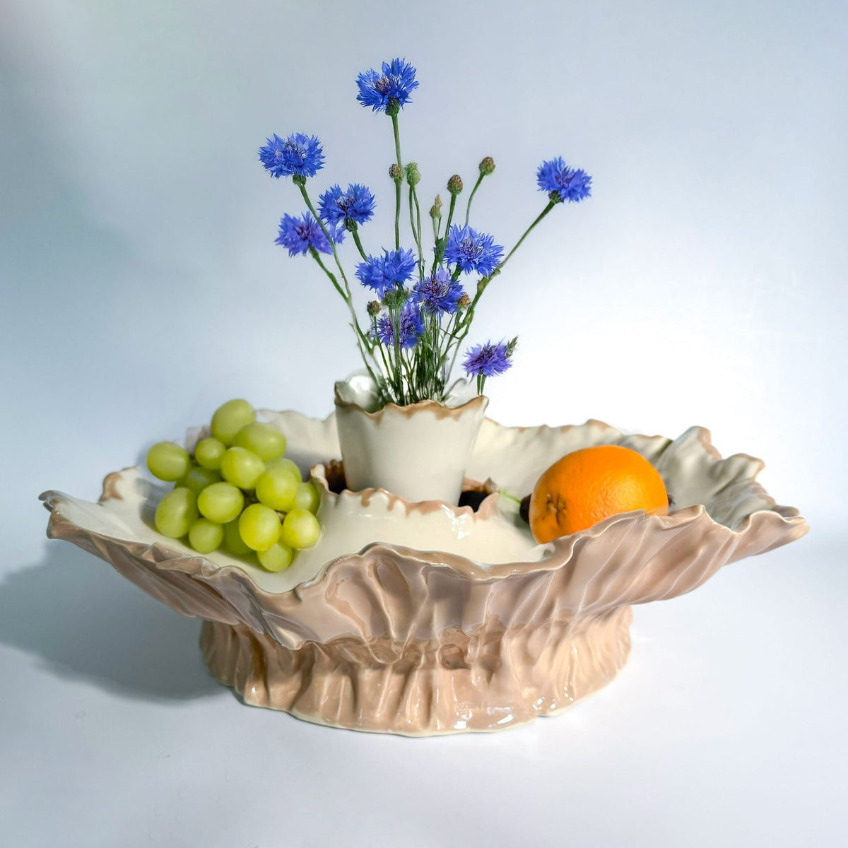 Blossom centerpiece porcelain fruit bowl with grapes, orange and a small vase of blue cornflowers