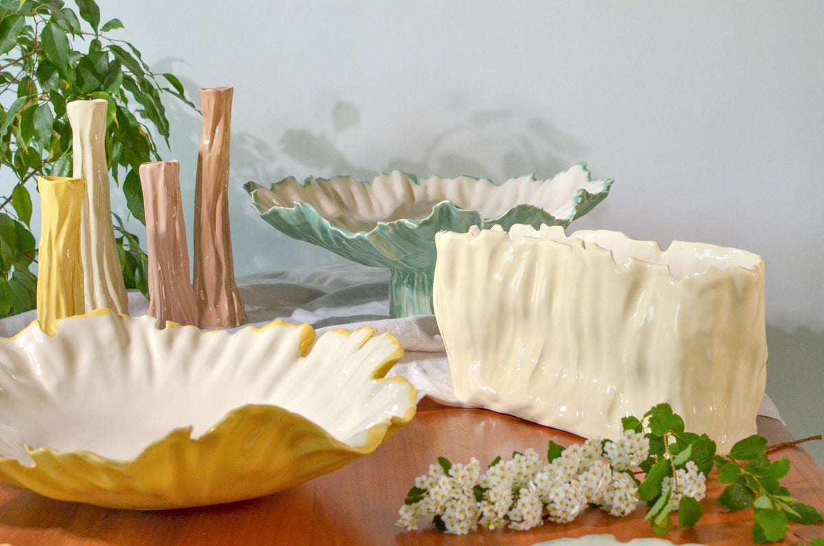 Blossom collection ivory porcelain bowls, tall vases and a textured cake stand on a wooden table
