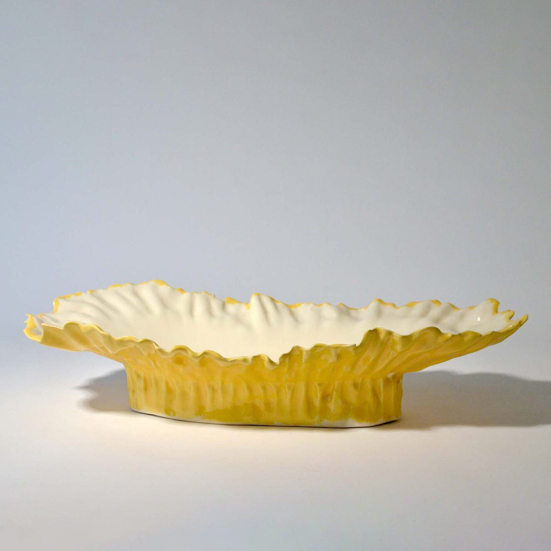 Blossom elevated serving bowl with a yellow rippled exterior and white interior, side view