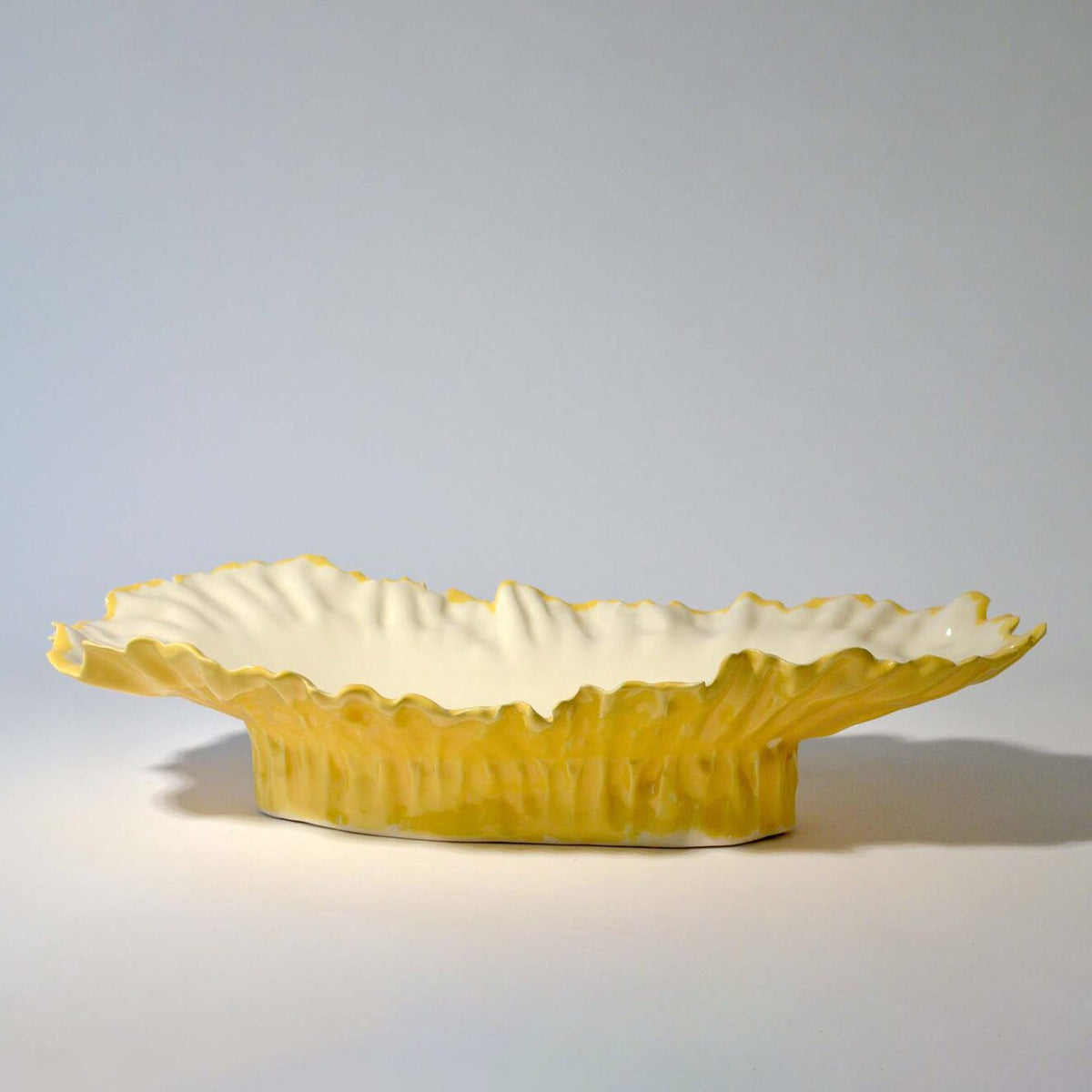 Blossom elevated serving bowl with a yellow rippled exterior and white interior, side view