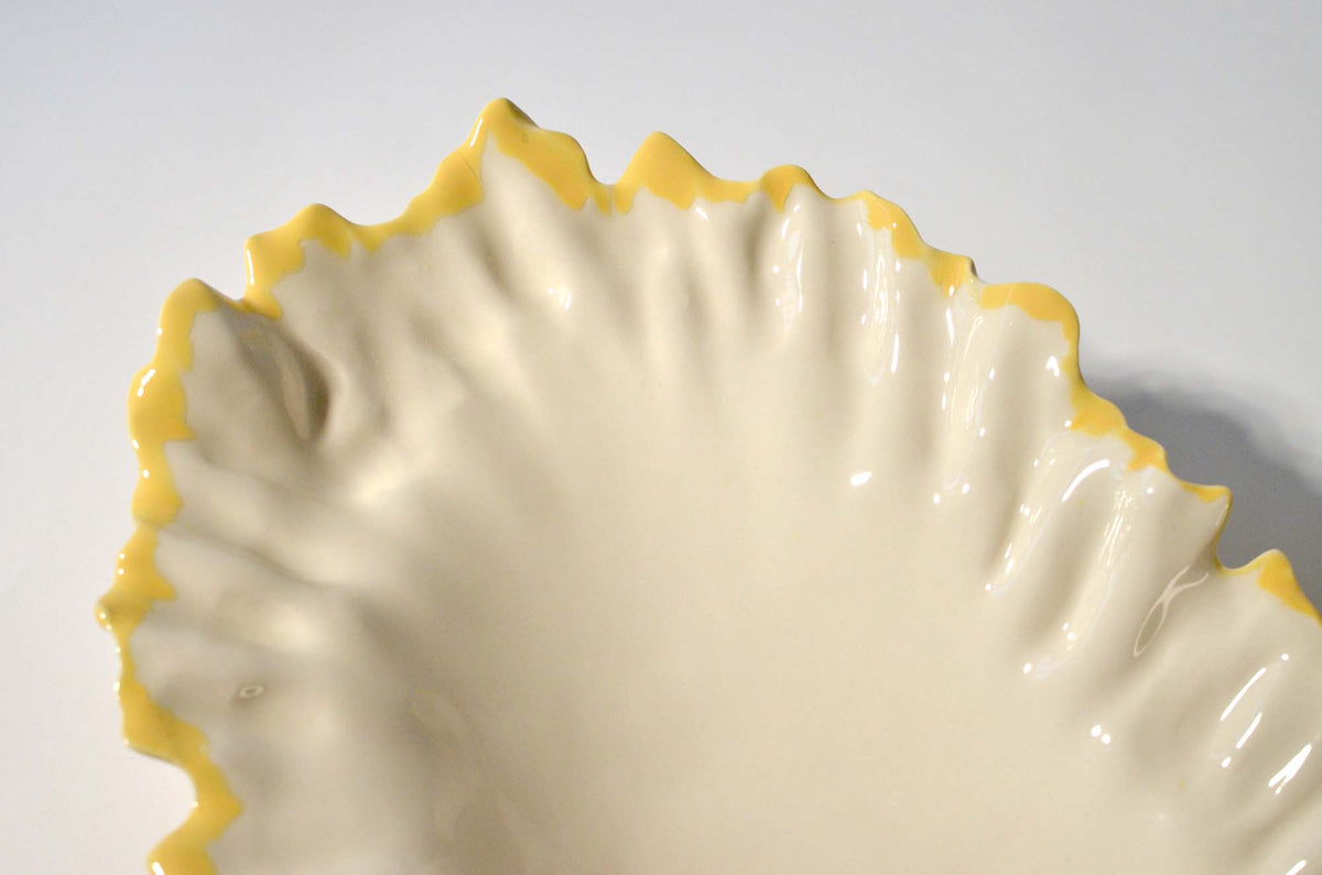 Close-up of the rippled white interior and yellow petal-like rim of the Blossom serving bowl