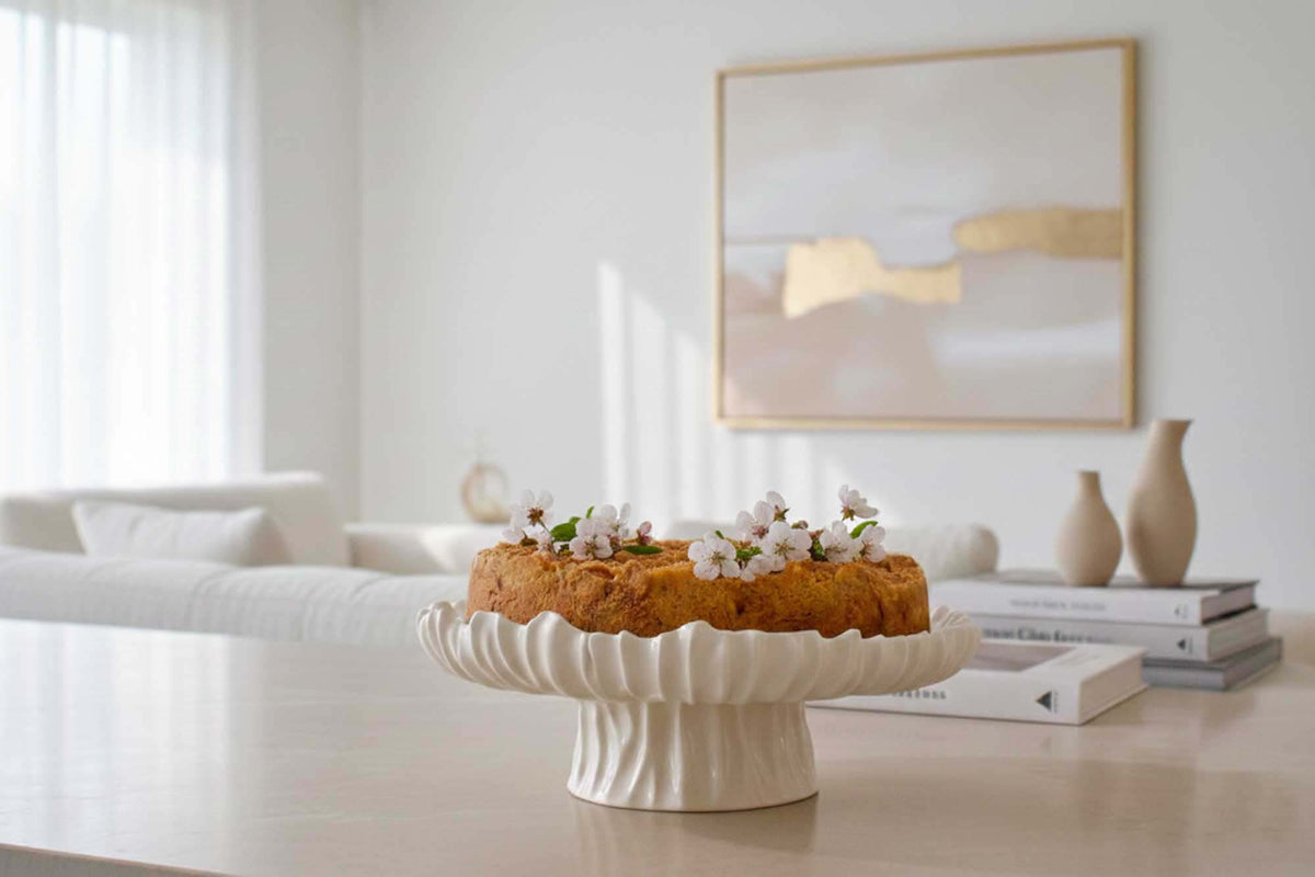 Ivory Blossom ceramic cake stand with a fluted pedestal holding a tart