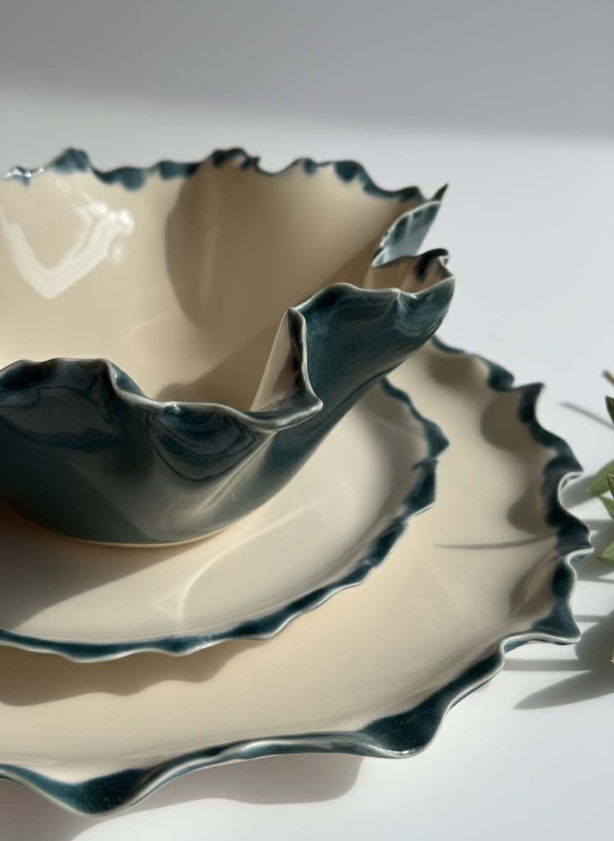 Stacked Blossom collection porcelain plates and bowl with wavy petrol green rims in ivory glaze