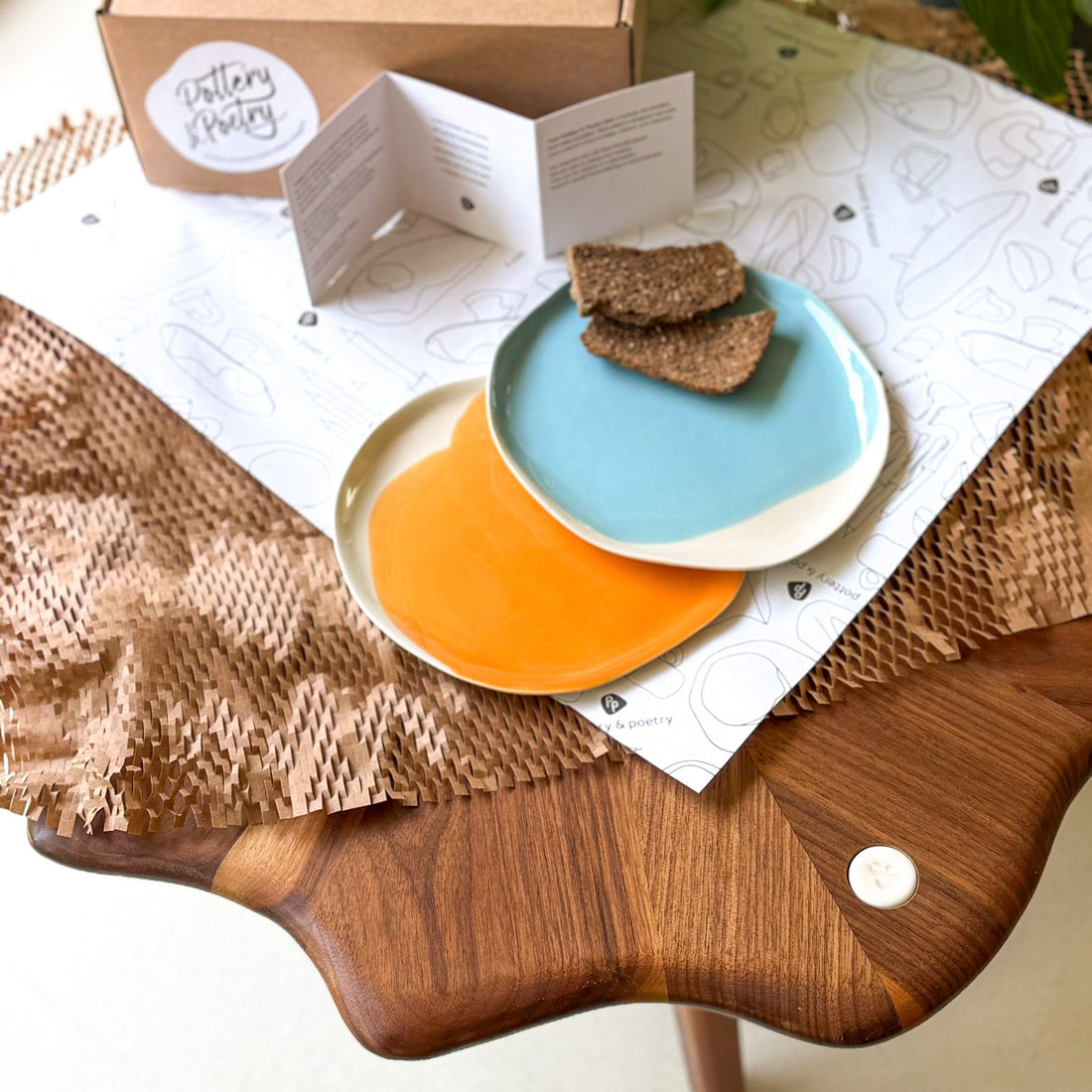 Two handmade dessert plates in turquoise and orange glazes, with pastries on a table