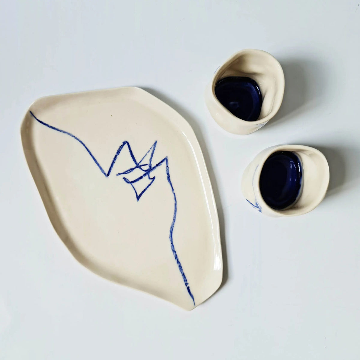 Archive porcelain platter with a blue line drawing beside two small bowls glazed deep blue inside
