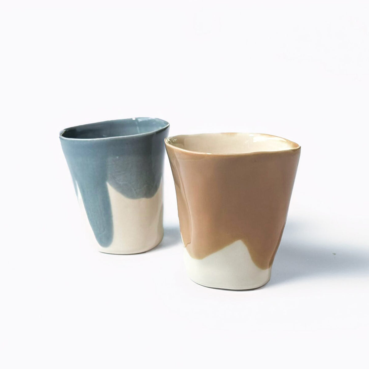 Two handmade ceramic cups with grey-blue and beige glazes