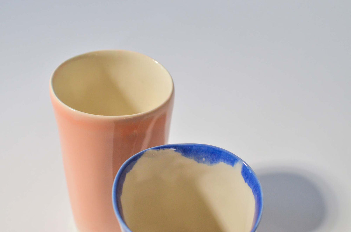 Milky Pink porcelain cup beside a small bowl with a blue rim, handmade ceramic tableware