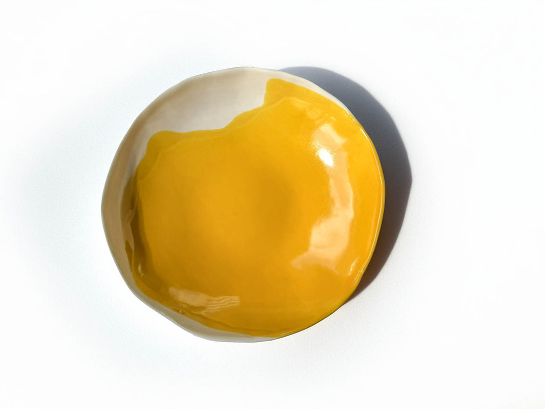 Organic-shaped porcelain serving bowl in Cadmium Yellow glaze, seen from above on white