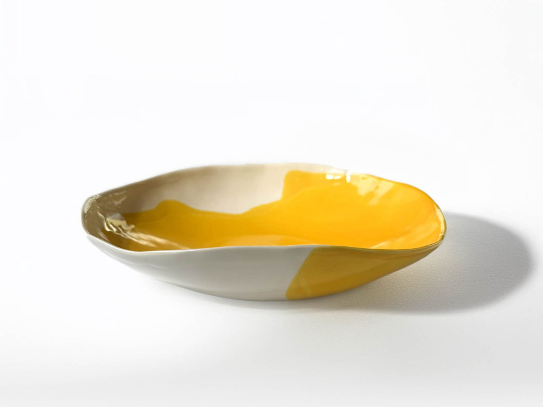 Low handmade porcelain serving bowl in Cadmium Yellow glaze with a white edge, side view
