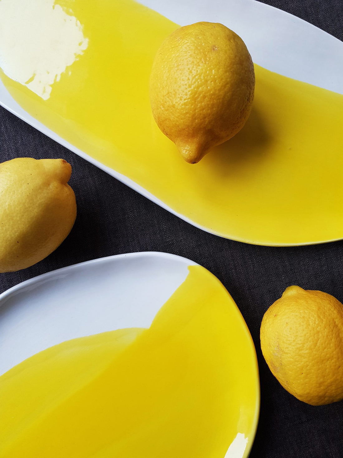Oval porcelain serving platters in Lemon Yellow glaze with white edges, styled with whole lemons