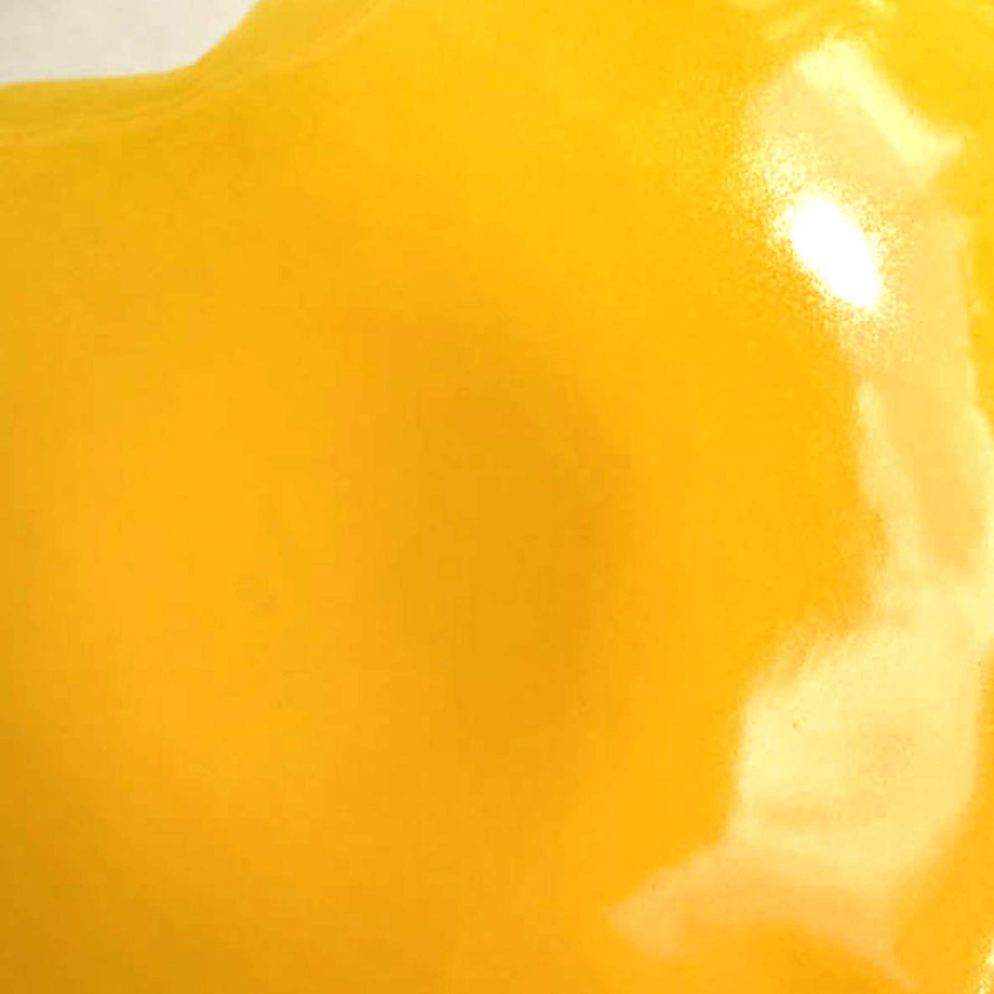 Cadmium Yellow glossy glaze sample on handmade porcelain with soft light reflections
