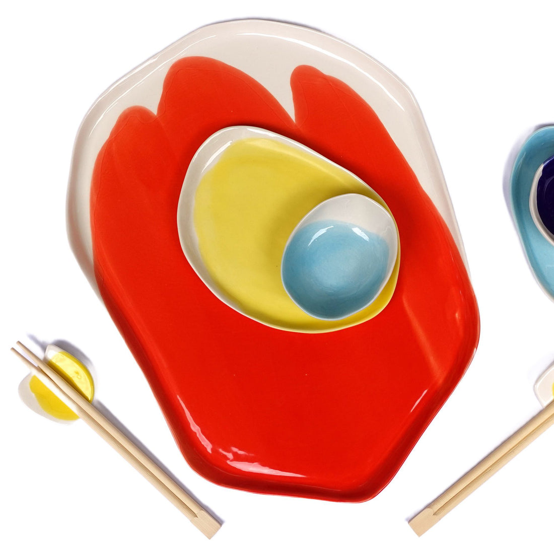 Red Scarlet porcelain plate layered with yellow and sky blue dishes, set with wooden chopsticks
