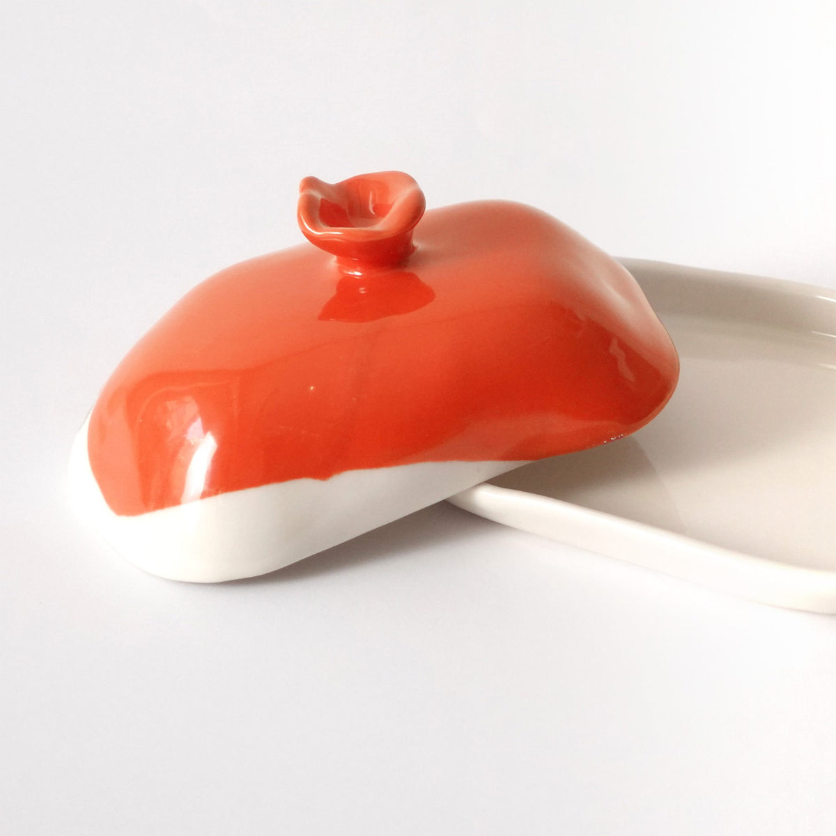 Handmade porcelain butter dish with a Ferrari Red lid and sculpted knob on a white base