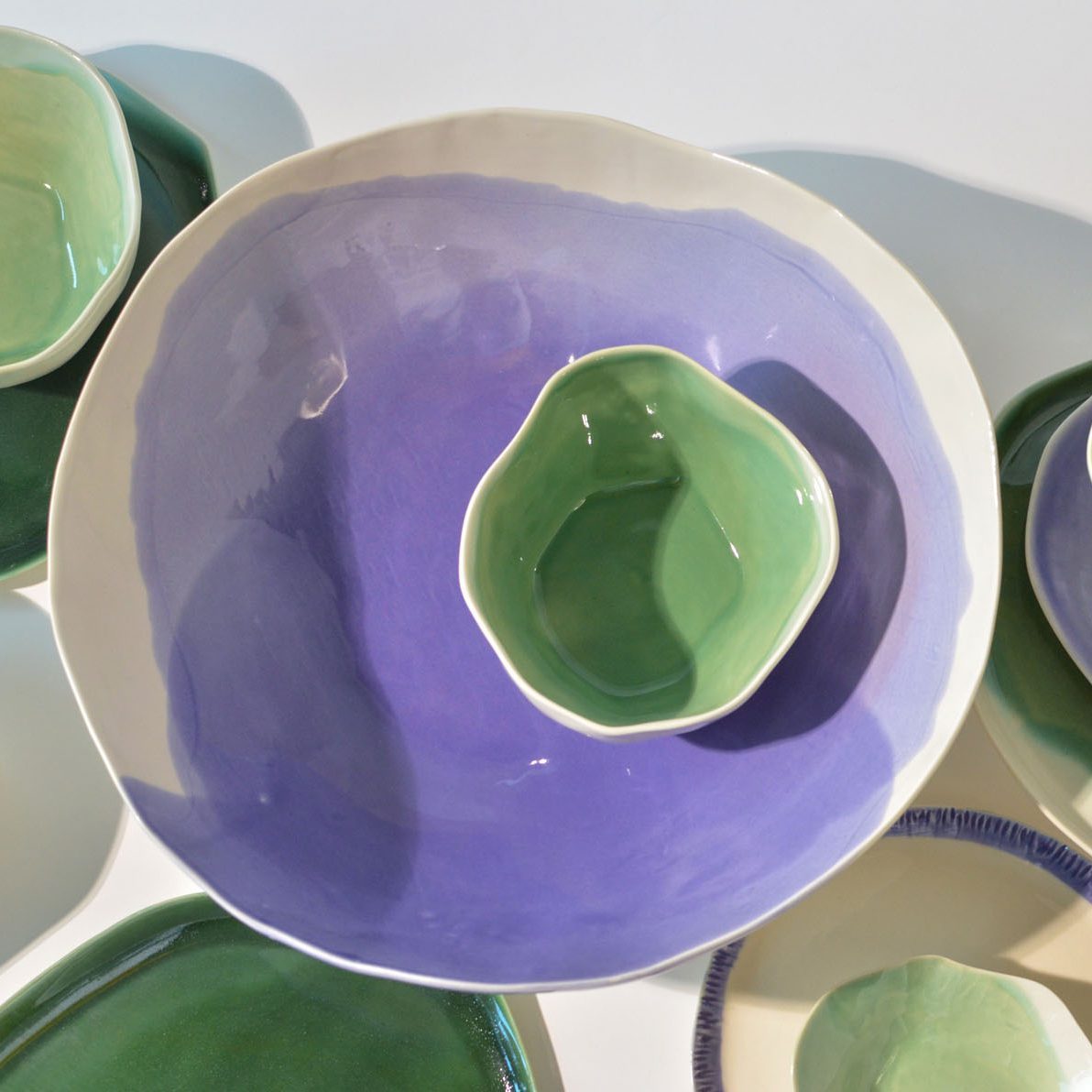 Lavender glazed porcelain bowl holding a Sage Green bowl, surrounded by green tableware